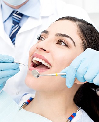 Woman smiling as dentist in blue gloves examines her mouth