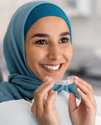 Woman in blue headwrap inserting Invisalign