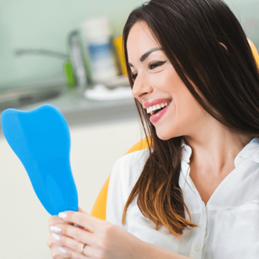 A smiling woman sitting in a dentist’s chair and admiring her pretty teeth