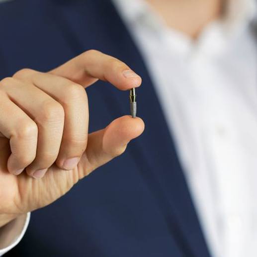 Man in business clothes holding a dental implant post