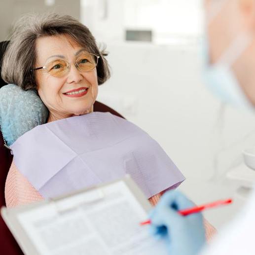 Dentist jotting notes during consultation with senior patient