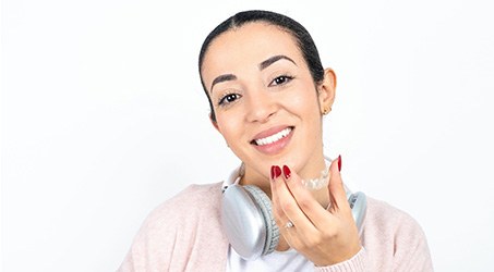 Smiling young woman holding Invisalign tray