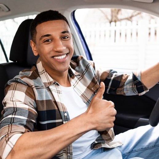 Man smiles and gives thumbs up in car