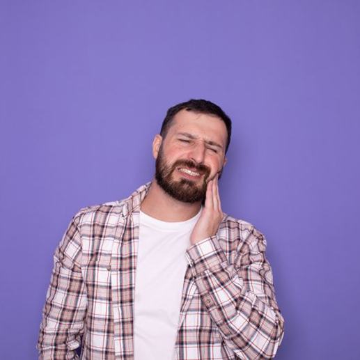 Man standing against purple background, struggling with dental pain