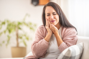 Woman sitting on couch with a toothache